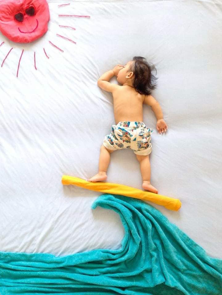 Baby surfing on beach background with towels